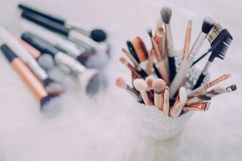A cup full of soft pink and white makeup brushes